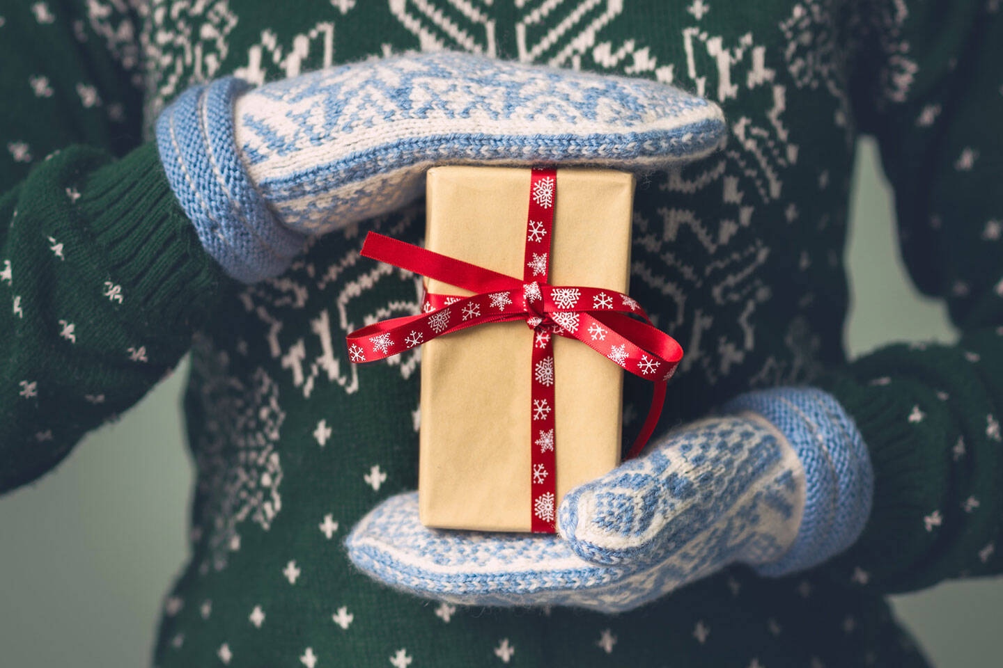 Hands in mittens holding a holiday gift